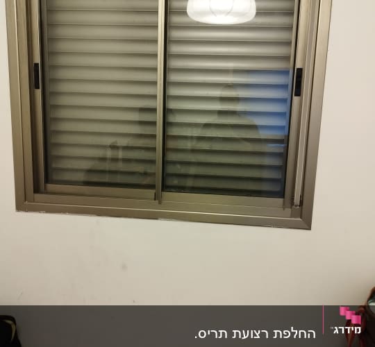 תריסים סגורים בחלון עם מסגרת מתכת